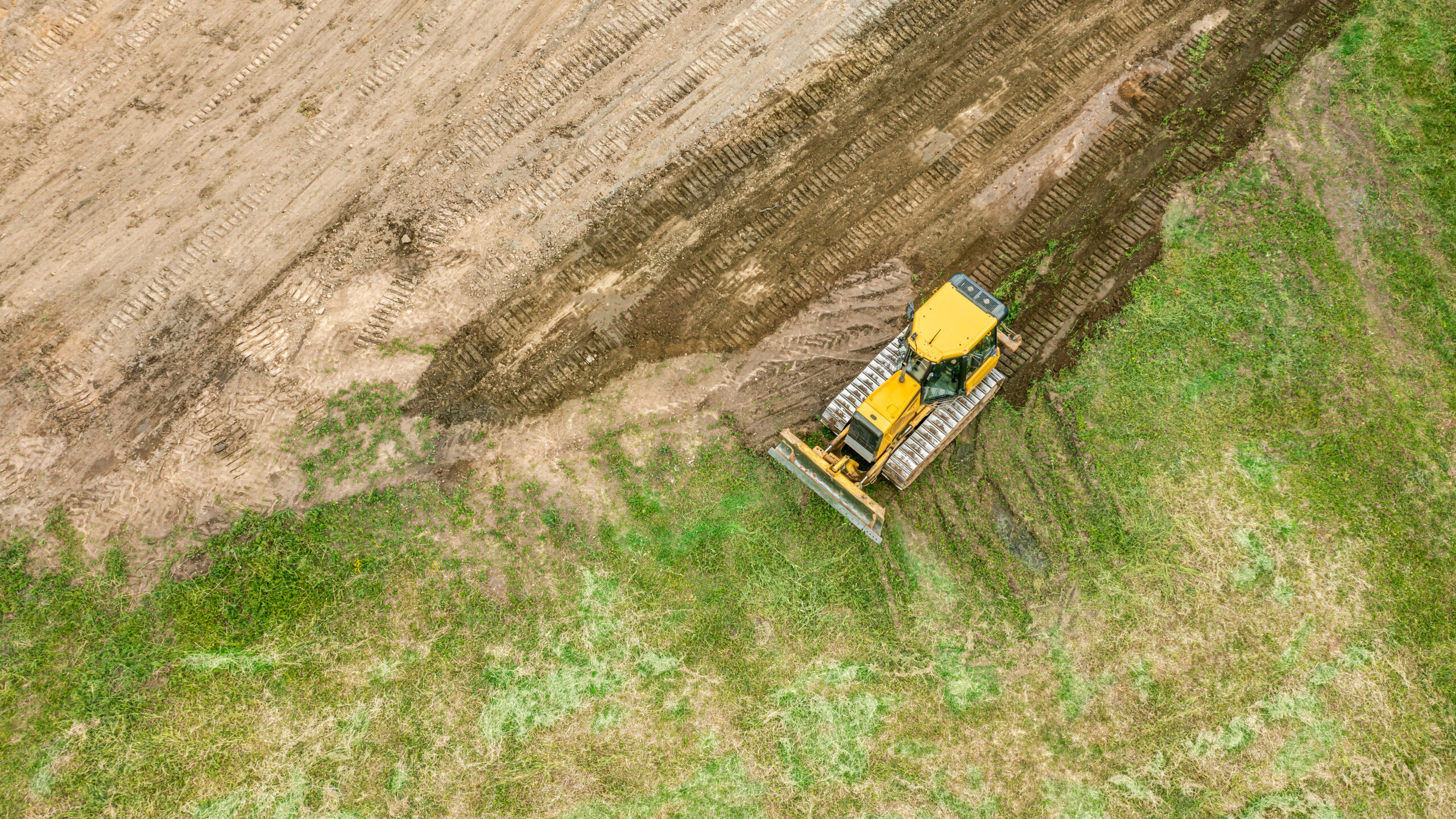 yellow bulldozer is moving and flattening soil. earthworks on construction site. aerial photo.