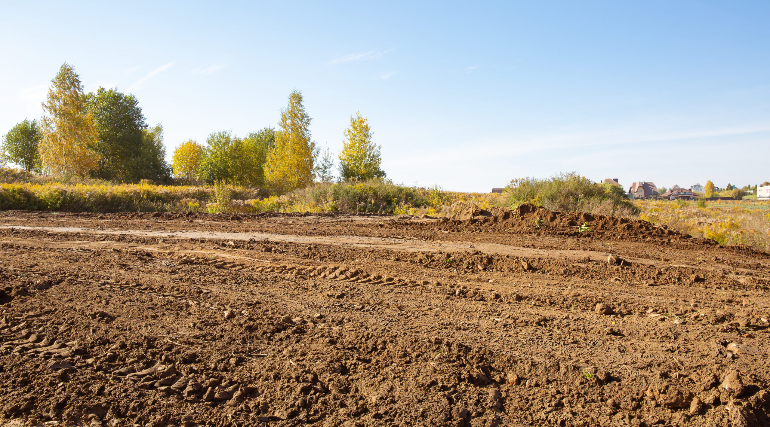 Empty land plot with tire prints prepared for new housing in rural area. Clearing and leveling of construction site. Earthworks for landscape design. Land reclamation for private property development